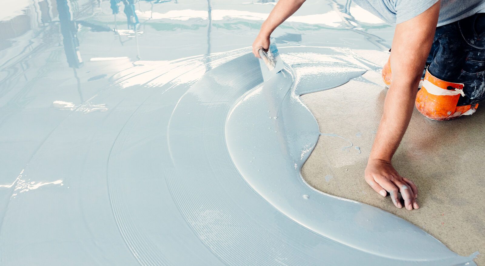 Self-leveling coating being spread across a concrete floor
