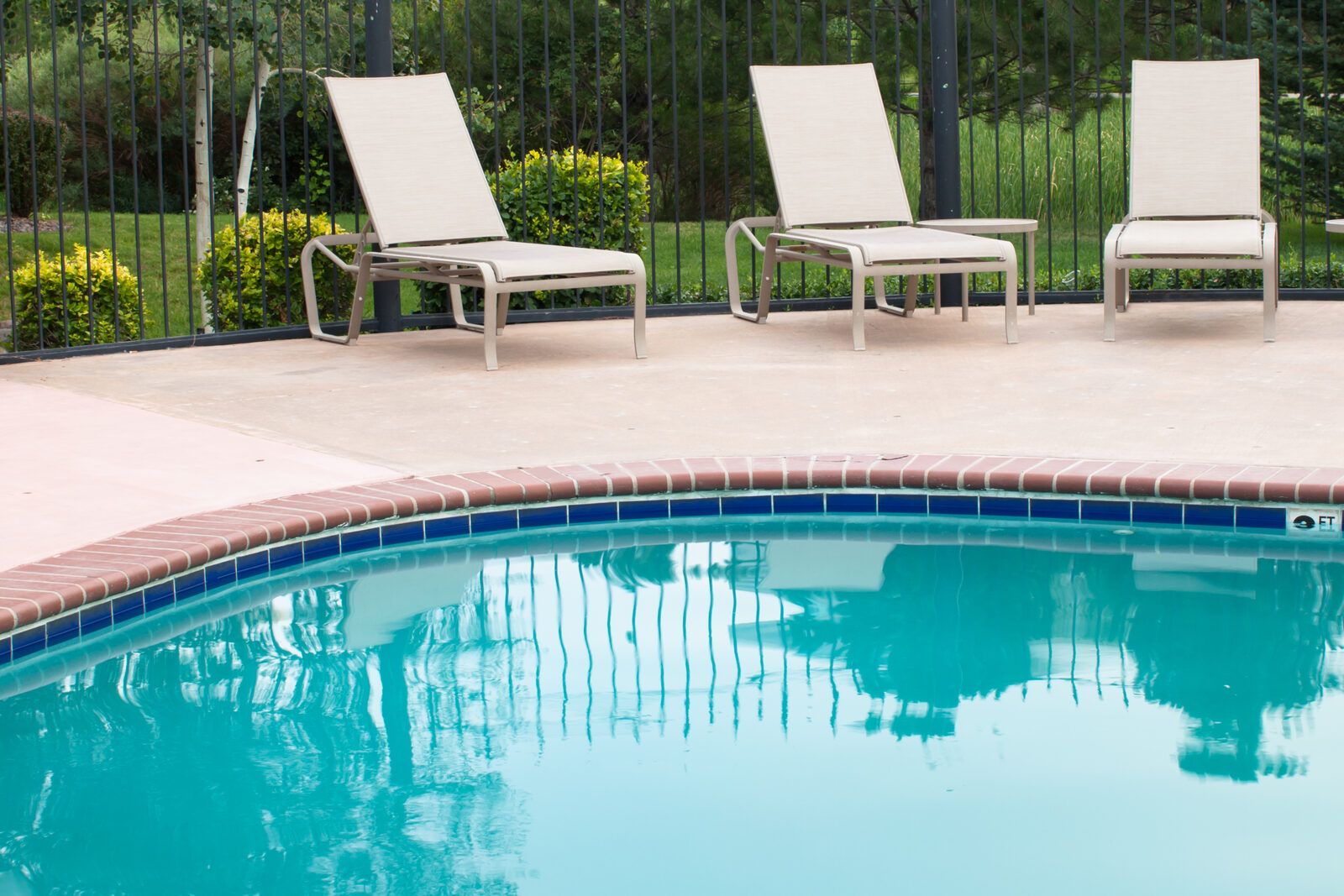 Coated pool deck with lounge chairs beside a turquoise pool